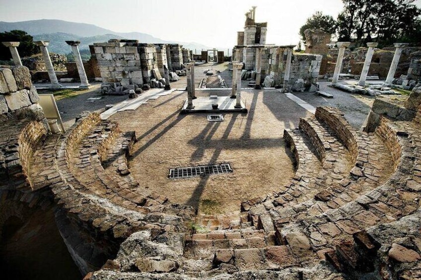 Ein uraltes Amphitheater mit Steinsitzen und Säulen, umgeben von Ruinen. 3
