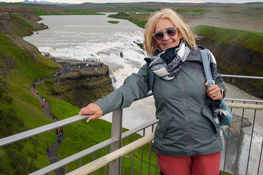 A person standing on a bridge overlooking a river with a waterfall. 1