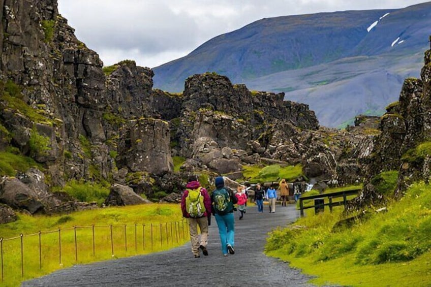 A rocky pathway with hikers, surrounded by rugged terrain and a mountain in the background. 4