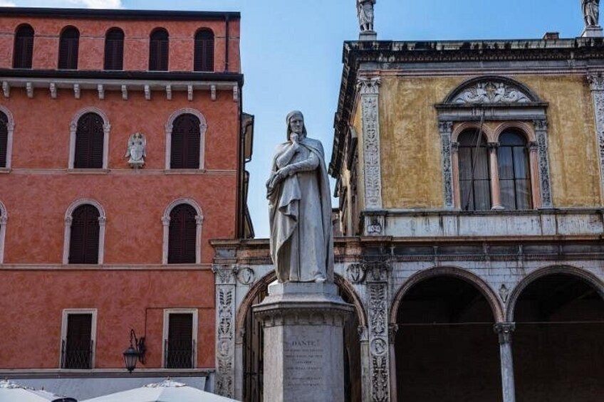 A statue in front of a red building with arched windows and a yellow building with a decorative facade. 5