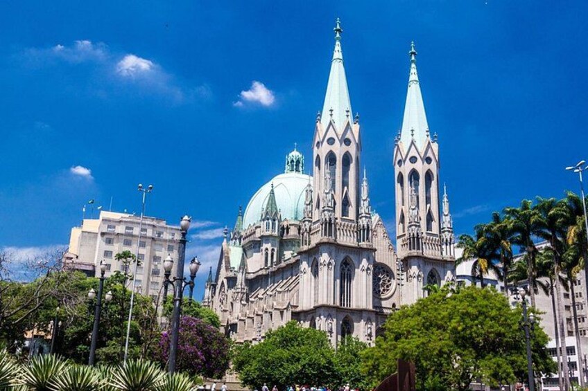 A cathedral with two tall spires and a dome, surrounded by trees and buildings. 1