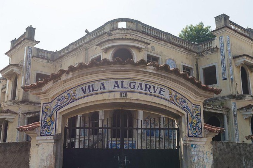 Entrada de un edificio histórico con decoraciones ornamentales y el nombre 'Vila Algarve' sobre la puerta. 4