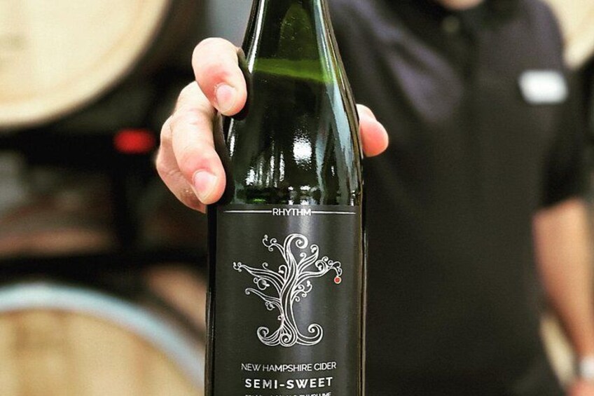 A person holding a bottle of New Hampshire Cider with a semi-sweet label. 2