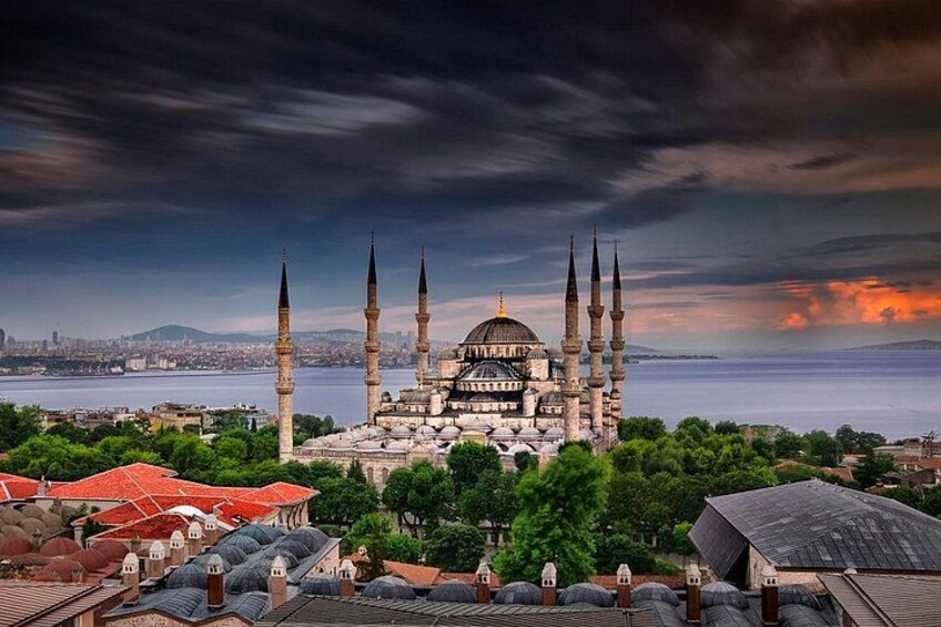 A historic mosque with multiple minarets, surrounded by lush greenery and a body of water. 5