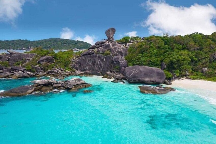 Un paisaje costero con aguas turquesas cristalinas, grandes rocas y colinas verdes exuberantes. 1