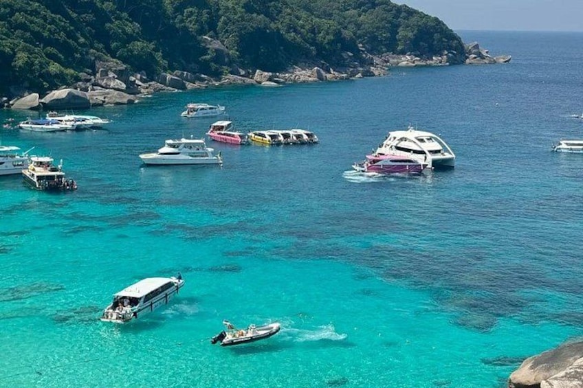 Un mar turquesa con barcos, una costa rocosa y abundante vegetación. 4