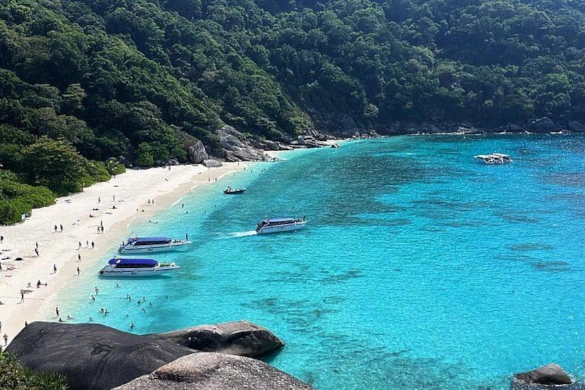 Una playa con aguas turquesas cristalinas, barcos y gente. 3