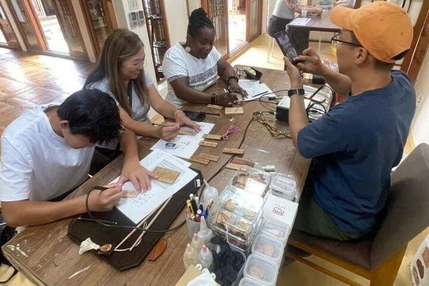 A group of people engaged in a workshop or class, with papers, tools, and containers on a table. 3