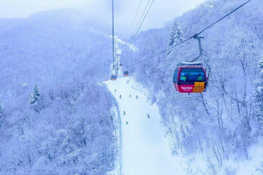 A red cable car ascending a snowy mountain path. 1