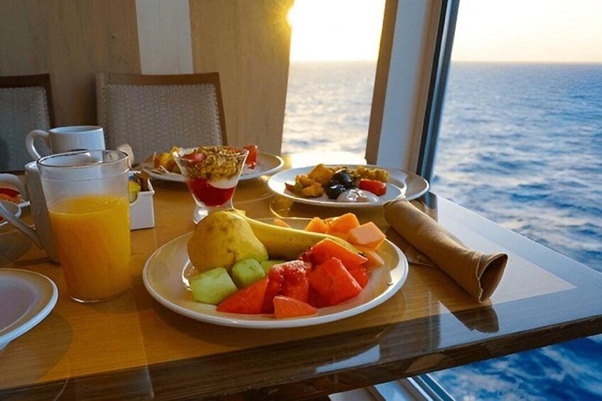 Et morgenbord med frugt, et glas appelsinjuice og havudsigt. 2