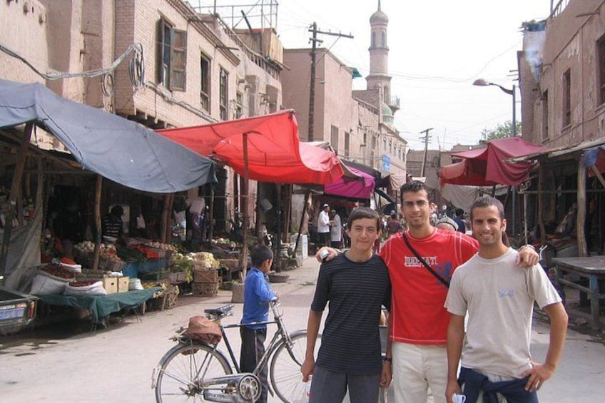 A street market with stalls, a bicycle, and buildings with a minaret. 1