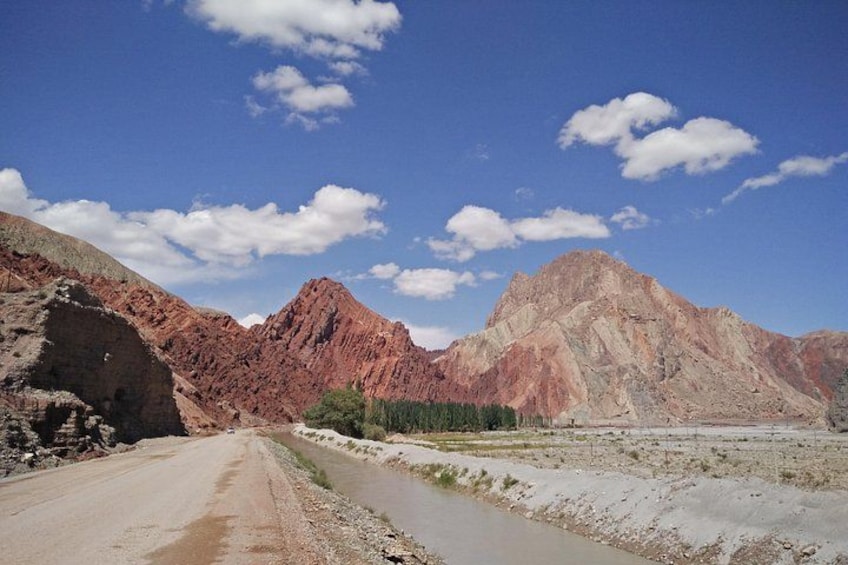 A mountainous landscape with a dirt road and a river. 3