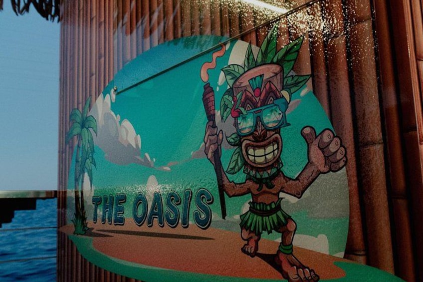 A tropical-themed sign with a cartoon character and the text 'THE OASIS'. 3