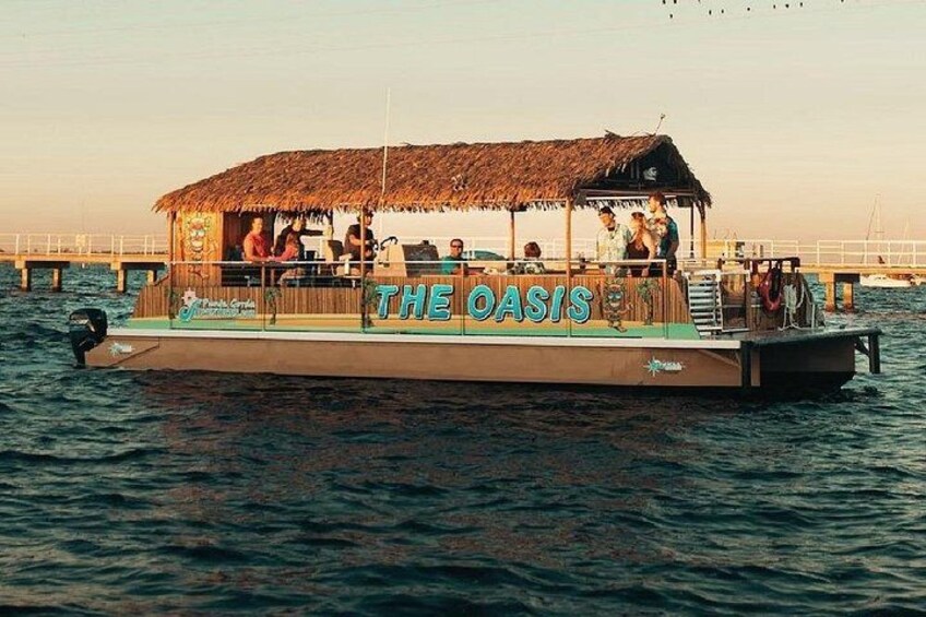 A boat named 'The Oasis' with a thatched roof and passengers. 4