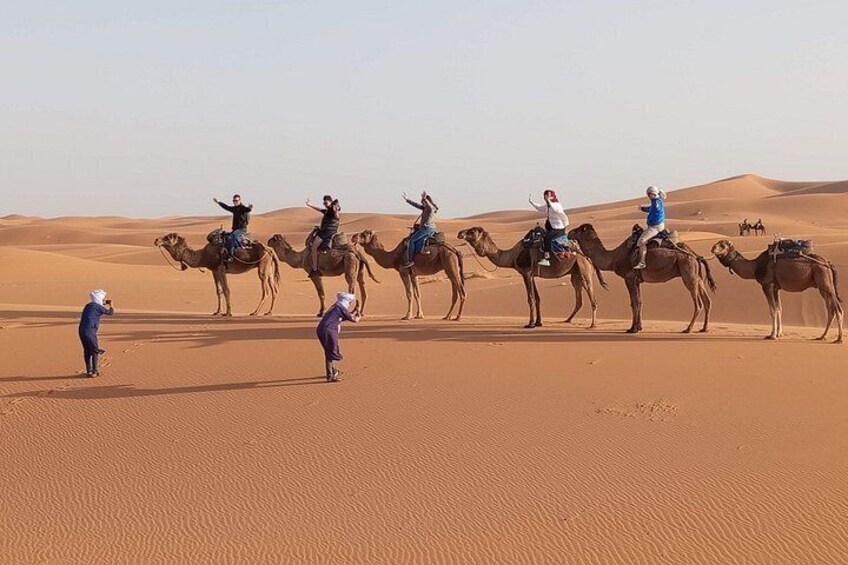 A group of people riding camels across a desert landscape. 4