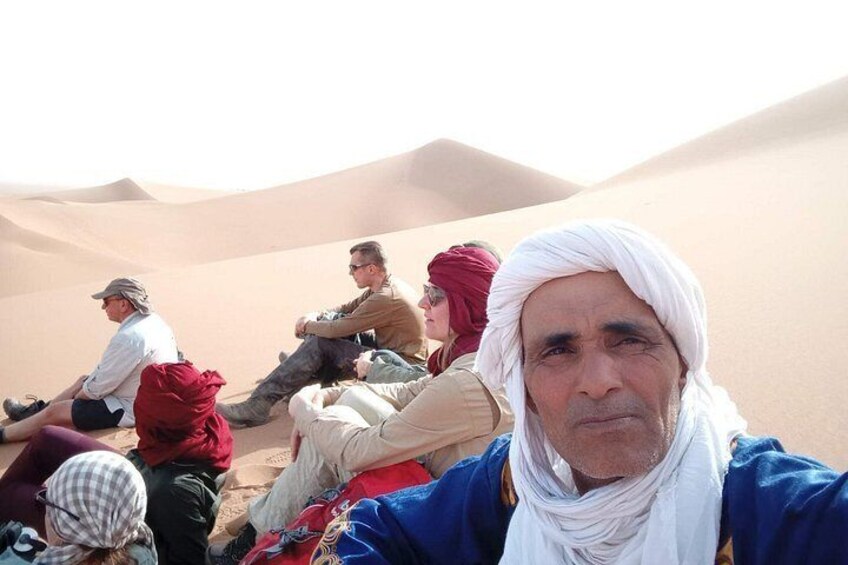 A group of people sitting on a dune in a desert landscape. 3