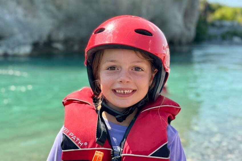 A person wearing a red helmet and a life jacket with 'SUPATH' written on it, standing by a body of water with a rocky background. 3