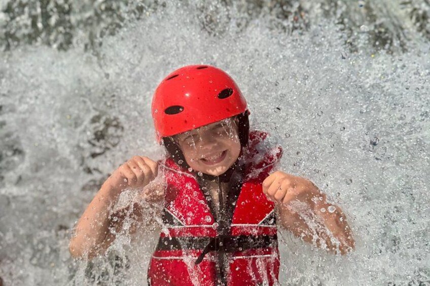 A person in a red helmet and life jacket, splashing water. 2