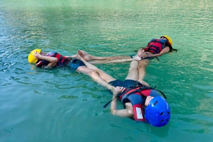 Twee personen drijven op kalm water, ze dragen reddingsvesten en helmen. 4