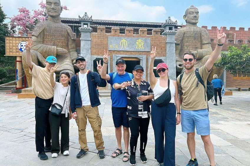 A group of people posing in front of a large statue and a traditional building. 5