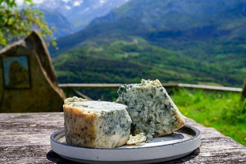 A cheese wheel on a plate with a mountainous landscape in the background. 3