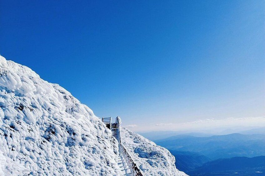 A snow-covered mountain with a chairlift and a clear blue sky. 1