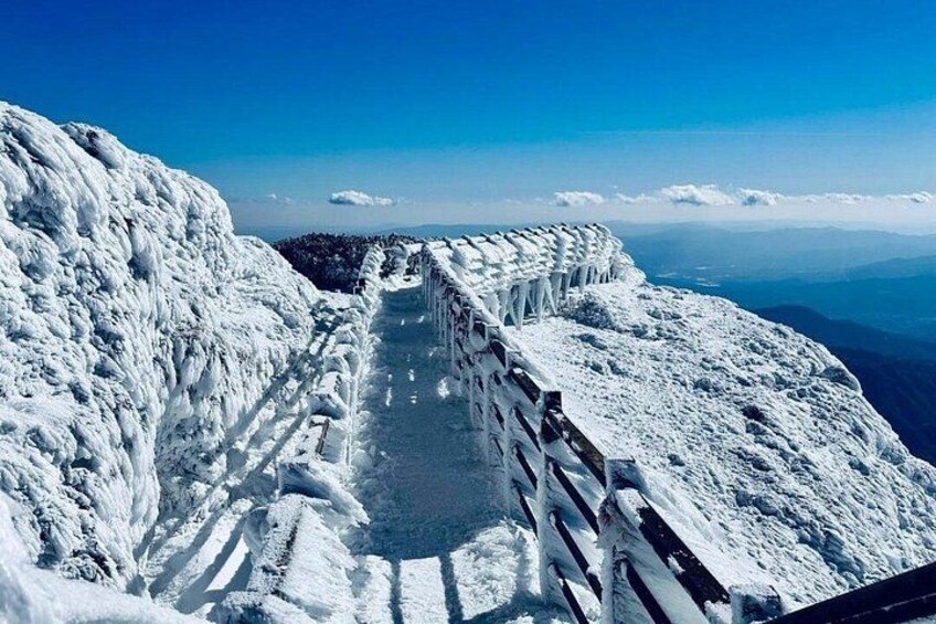 A snow-covered mountain path with a wooden railing. 2