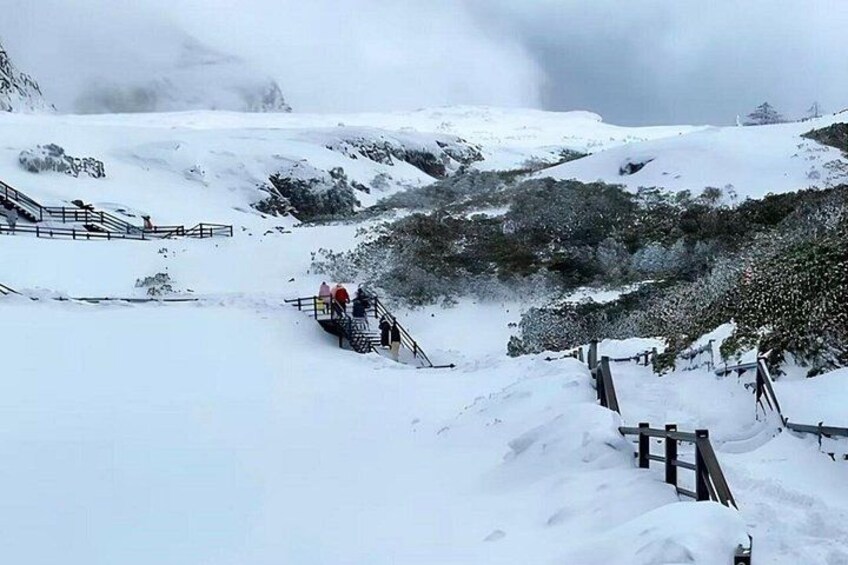 Un paisaje montañoso nevado con una escalera de madera que sube. 2