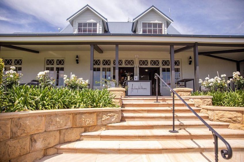 A two-story house with a covered porch, stone steps, and white flowers. 2