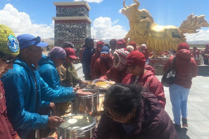 A group of people at a food stall with a large golden lion statue in the background. 2