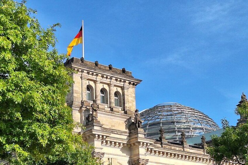 Un edificio histórico con una bandera, una cúpula y árboles. 4