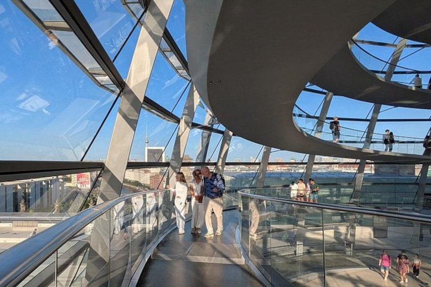 Una estructura moderna de vidrio y acero con personas caminando sobre un piso de vidrio. 4