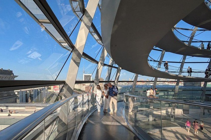 Una estructura moderna de vidrio y acero con personas caminando sobre un puente de cristal. 1