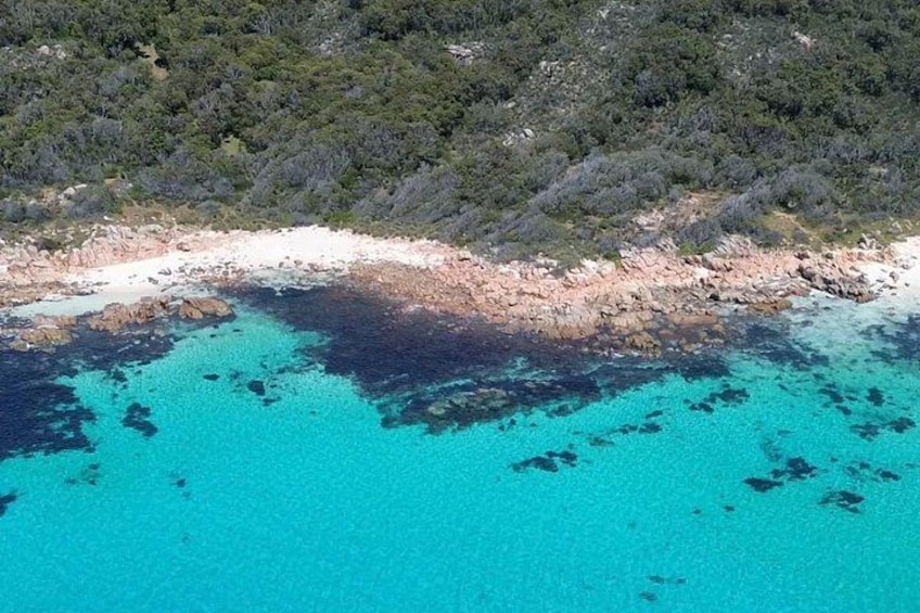 Un paysage côtier caractérisé par une eau turquoise cristalline, une côte rocheuse et des collines densément boisées. 5