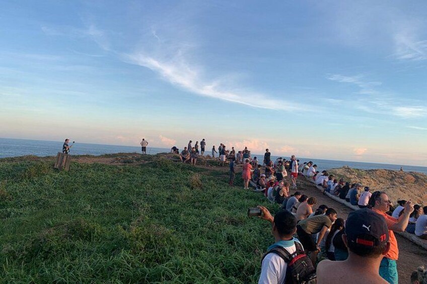 Un grupo de personas reunidas en una colina cubierta de hierba con vistas a un cuerpo de agua. 4