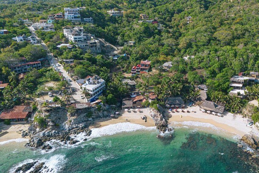 A coastal town with buildings, a beach, and a rocky outcrop. 2
