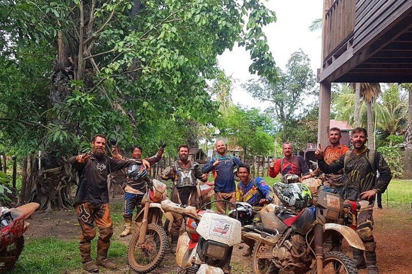 A group of people with dirt bikes in a forested area. 1
