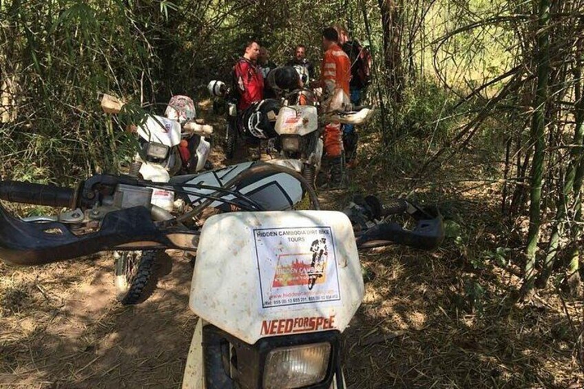 A group of people gathered around a quad bike in a forested area. 2