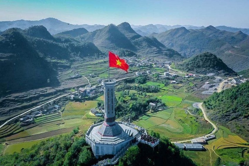 A flag atop a tower, a rural landscape with fields, and a mountainous backdrop. 5