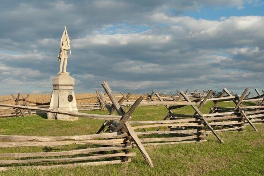 Una estatua sobre un pedestal, rodeada de vallas de madera en un campo cubierto de césped. 2