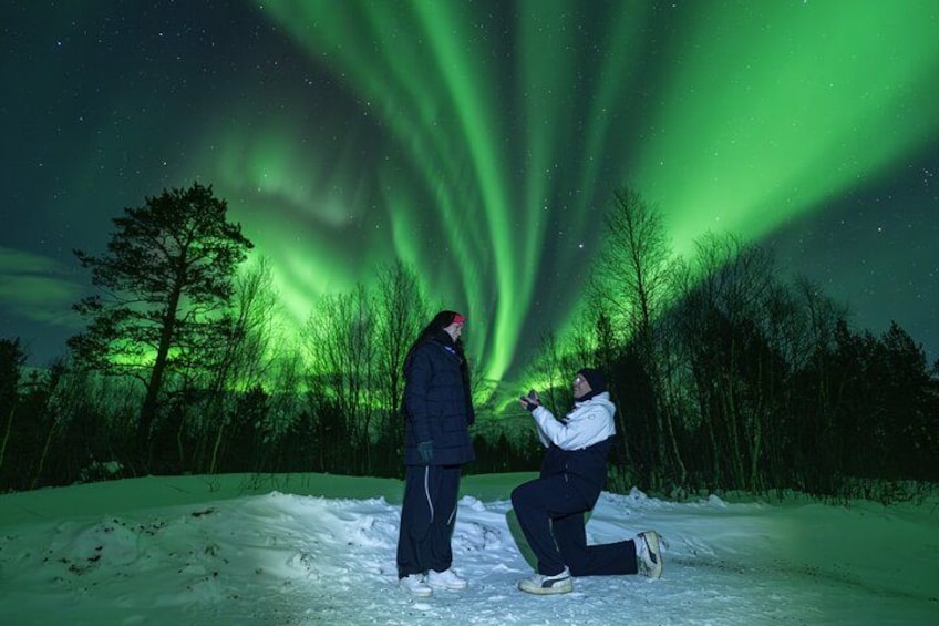 A person kneeling in snow under the aurora borealis. 1
