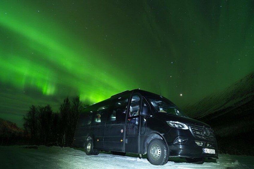 Un furgone nero parcheggiato su una superficie innevata sotto un'aurora verde. 2
