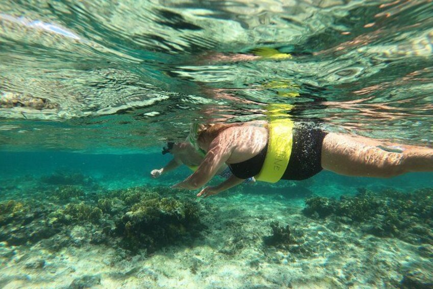 A person swimming underwater with a yellow wristband. 4
