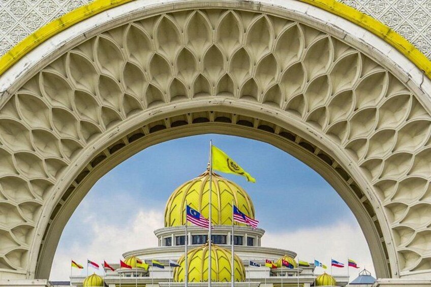 Un edificio de cúpula amarilla con banderas, debajo de un arco decorativo. 2