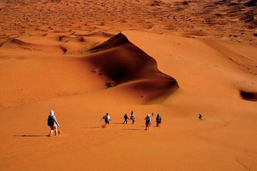 Un groupe de personnes fait une randonnée dans un désert de dunes de sable. 4