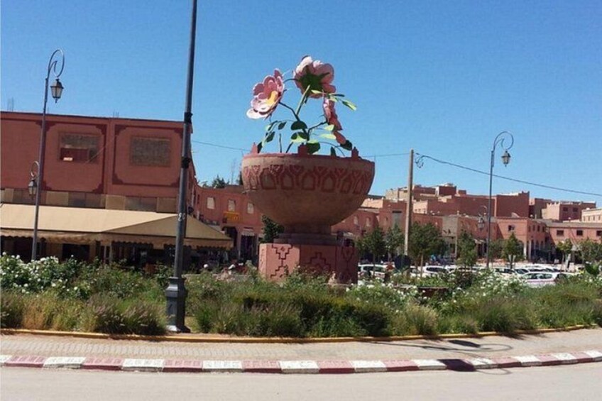 Un grand vase décoratif rempli de fleurs, une rue avec des voitures et des bâtiments en arrière-plan. 2