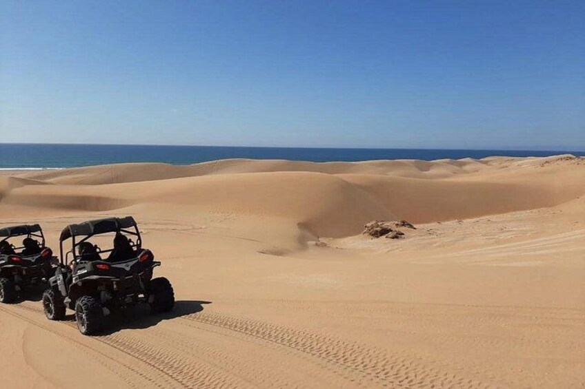 Off-road vehicles on a sandy terrain with dunes and a clear sky. 2