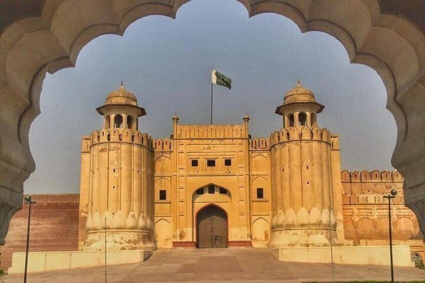 A historic building with a large archway, two towers, and a flag. 1