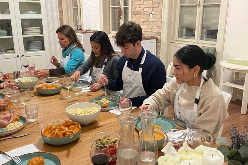 A group of people dining at a wooden table with various dishes and glasses. 1