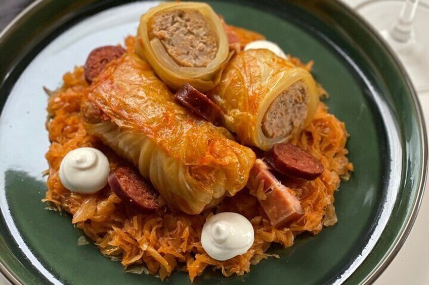 En ret med kålruller, skiver af pølse og klatte af creme fraiche på en tallerken. 5